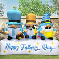 Three gnome inflatables in hats with mustaches on a Happy Father's Day base in a garden
