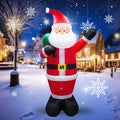 Tall Santa inflatable waving with a green sack in a snowy village at night