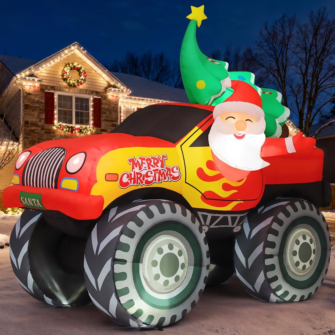 Santa driving a red and yellow monster truck inflatable with flame decals and a tree in the back