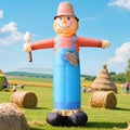 Tall scarecrow inflatable in a straw hat and overalls in a field with hay bales
