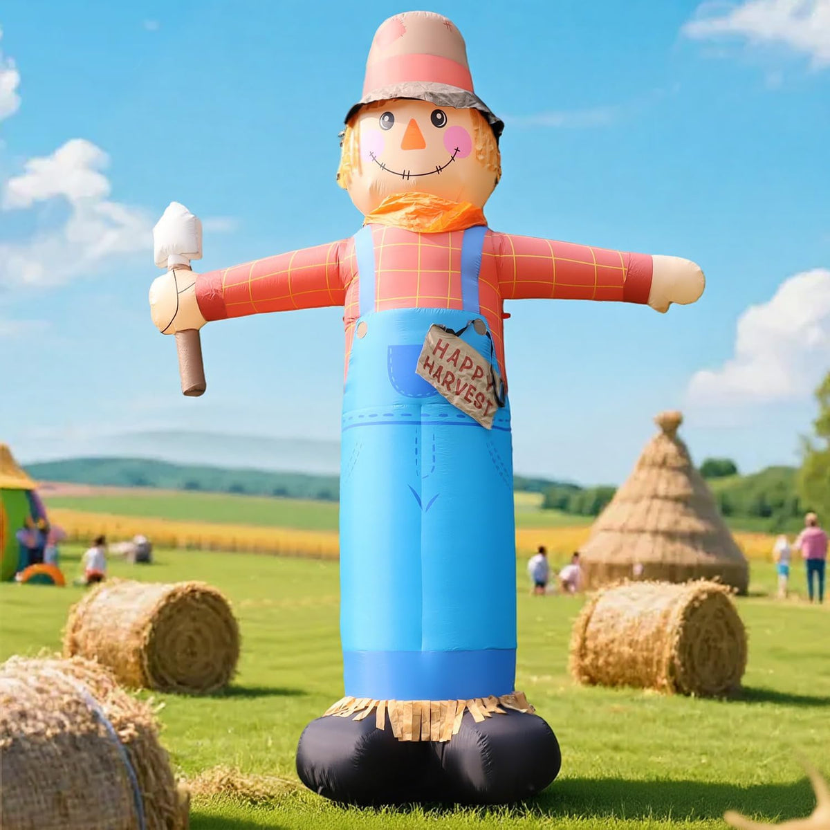 Tall scarecrow inflatable in a straw hat and overalls in a field with hay bales