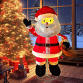 Sparkling lighted Santa figure waving beside a decorated tree by a window