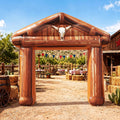 Wood-look ranch gate inflatable arch with a longhorn skull at a western ranch party