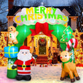 Green Merry Christmas arch inflatable with Santa, a reindeer and a gingerbread man in front of a lit house