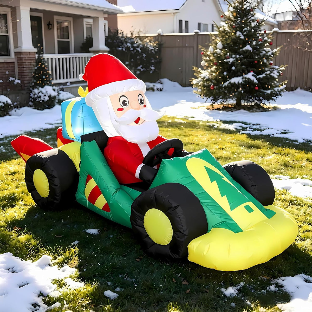 Santa driving a green and yellow race car inflatable in a snowy yard
