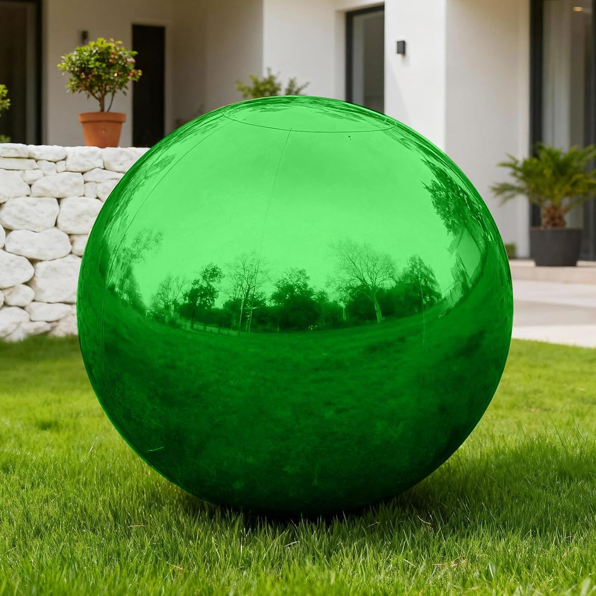 Glossy green inflatable mirror ball on a lawn in front of a house