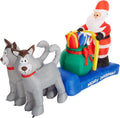 Santa on a blue Merry Christmas sled with a gift sack pulled by two gray huskies