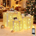 Three glittery gold lighted present boxes with bows under a Christmas tree