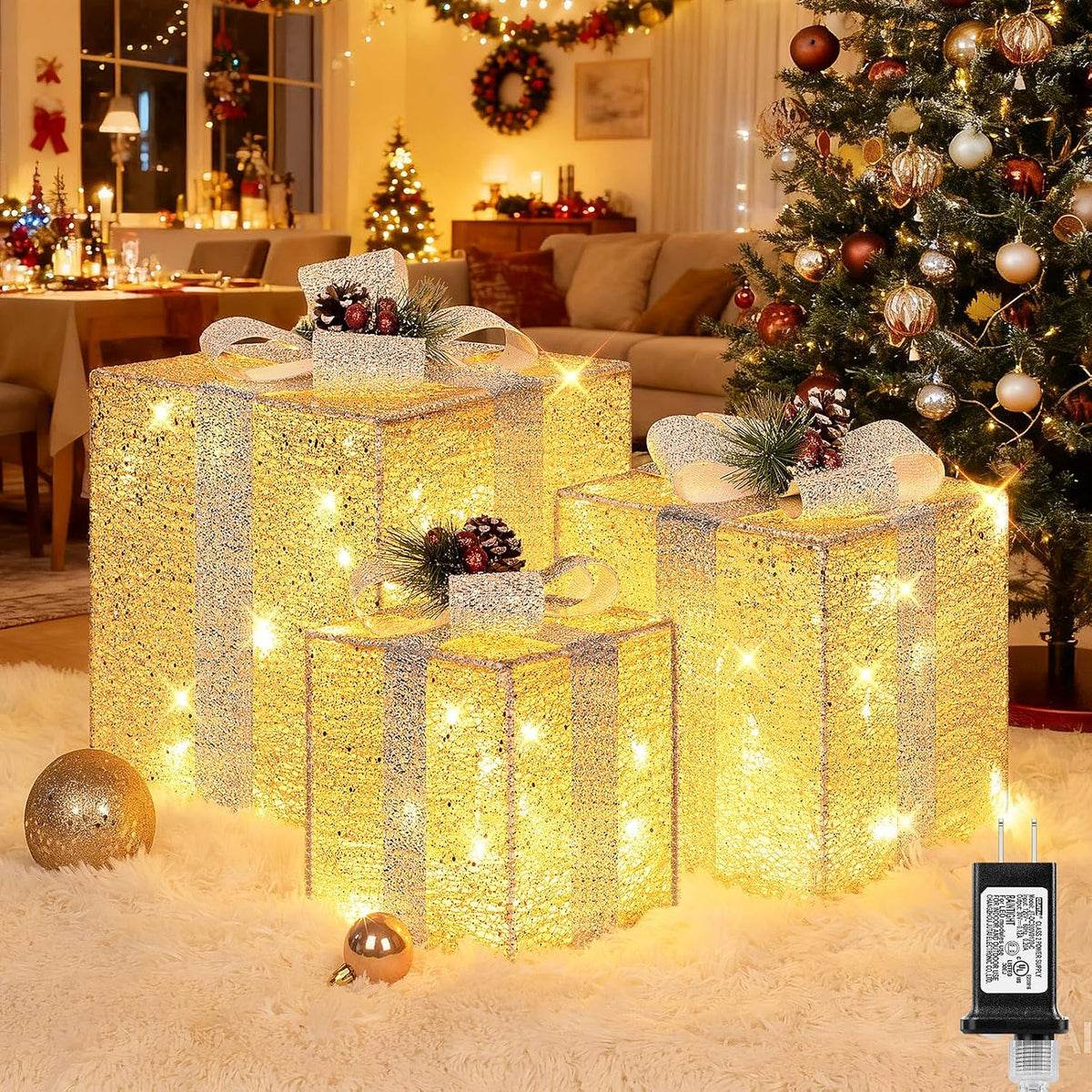 Three glittery gold lighted present boxes with bows under a Christmas tree